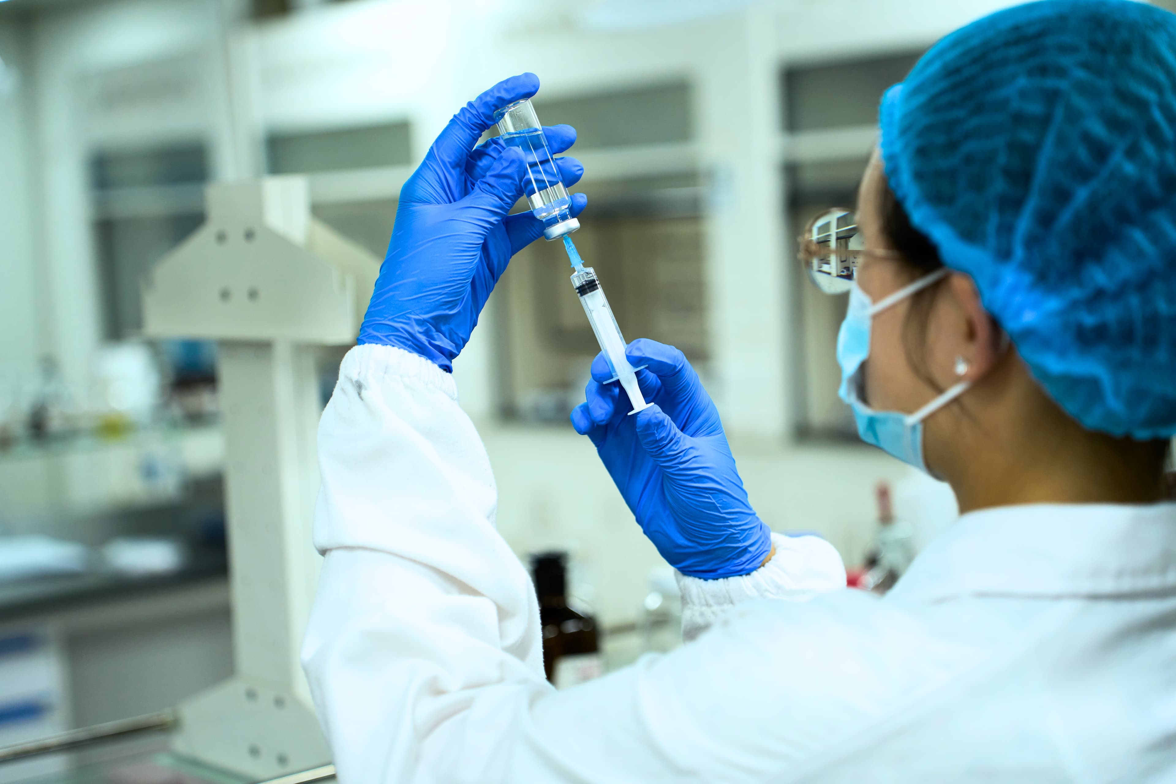 Laboratory worker drawing liquid from a vial with a syringe